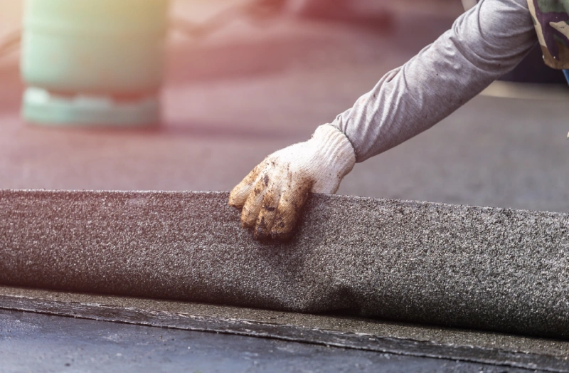 A person wearing gloves and holding onto the edge of a wall.