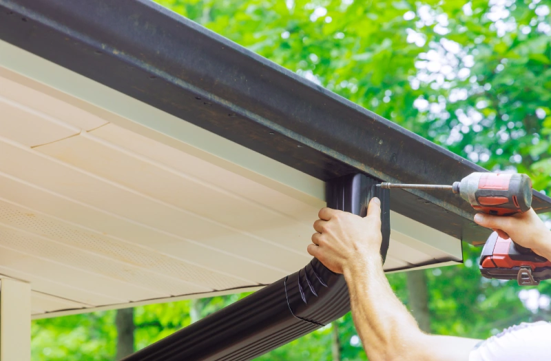 A person is holding the gutter on top of their roof.