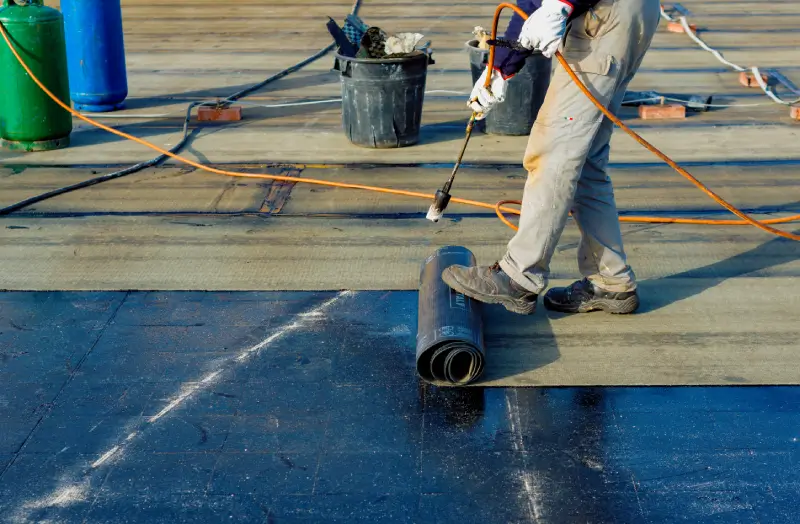 A man is spraying water on the roof of a building.
