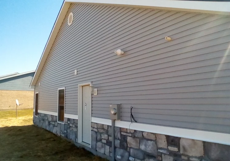 A house with stone siding and windows on the outside.