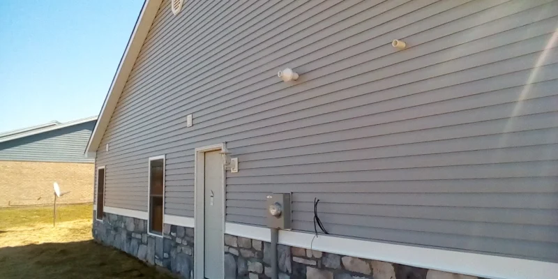A house with stone siding and windows on the outside.