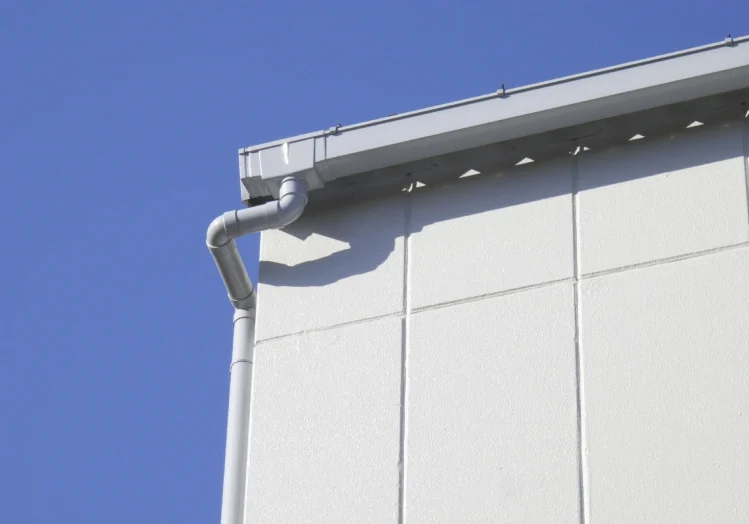 A white building with a metal gutter on the side.